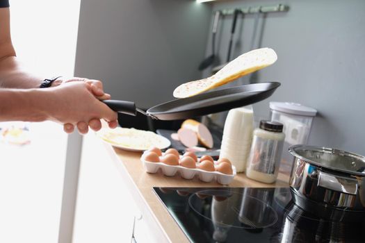A man fries tacos in a frying pan at home in the kitchen, close-up. Organic fast food, Cooking Ingredients