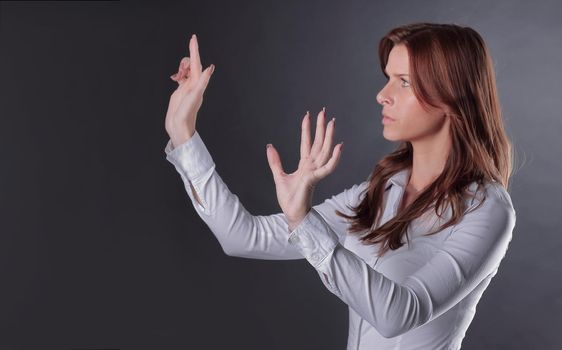 uncertain business woman clicks on the virtual button.isolated in the dark.photo with place for text