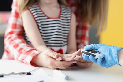 Close-up of doctor in laboratory taking blood of little girl thumb using lancet in clinic, standard procedure for checkup, analysis. Medicine, hospital, pediatrician appointment concept