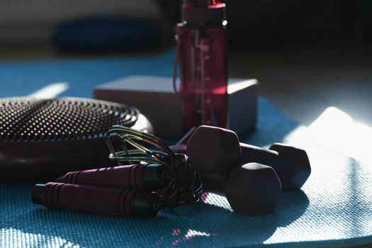 Sports fitness accessories, dumbbells and jump rope, close-up. Sports bottle and massage ball. Aerobics equipment