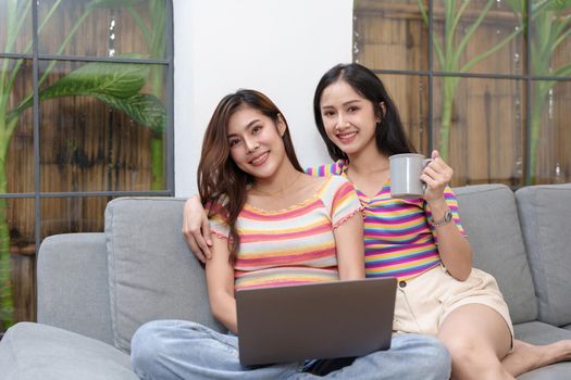 lgbtq, lgbt concept, homosexuality, portrait of two asian women posing happy together and loving each other while playing computer laptop on bed.