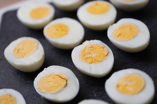Chicken halves boiled eggs set on a black background, close-up. Harmless food, organic production. Calorie content of food
