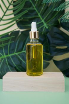 Cosmetic bottle with facial serum on a wooden podium. The concept of zero waste and ecology.