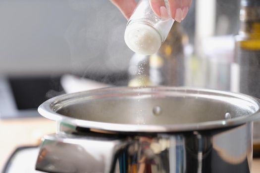 Woman prepares food in a saucepan and salt, close-up. Master class on cooking homemade food, using kitchen utensils