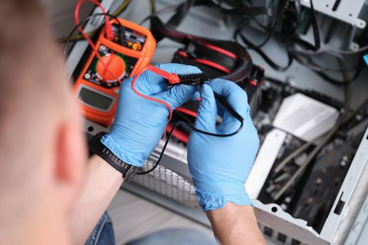 Man working with a multimeter to repair computers, close-up. Digital device, voltage measurement, upgrade pc