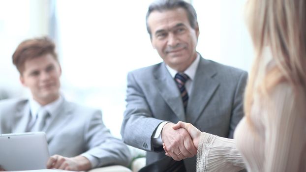 handshake of a businessman and the business woman behind a Desk.