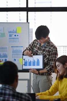 Confident businessman holding digital tablet with financial graph and giving presenting in meeting.