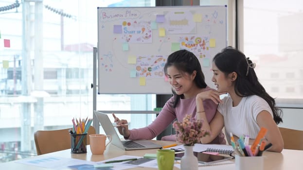 Shot of happy female entrepreneurs using laptop computer while working together in the office.