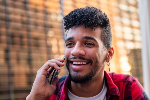 portrait of young latin man talking on the phone happy and smiling, concept of technology and urban lifestyle
