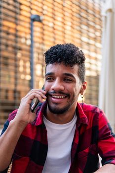 vertical portrait of young latin man talking on the phone happy and smiling, concept of technology and urban lifestyle