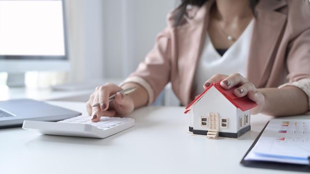 Businesswoman using calculator calculating account for buy house in the future. Property investment concept.