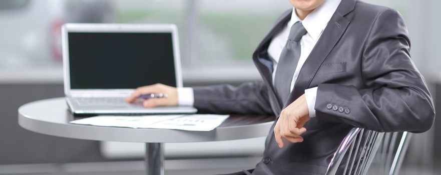 young businessman sitting at workplace and looking at camera.