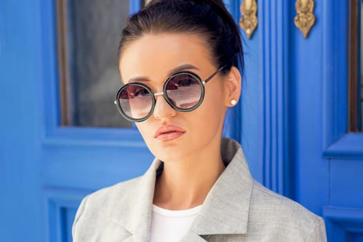 Woman wearing sunglasses using smartphone in the European city. Beautiful girl in the city near door.