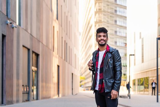 stylish young latin man smiling happy in the city, concept of urban lifestyle