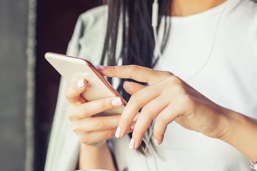 beautiful woman in glasses is listening music by her smartphone at cafe, she listens to music through headphones, portable, copy space