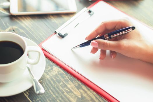 Closeup of a business woman hand is writing on a blank planner at cafe. Business concept. Copy space.
