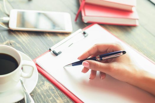 Close up of a hand of business woman writing by pen on a blank planner. Business concept.