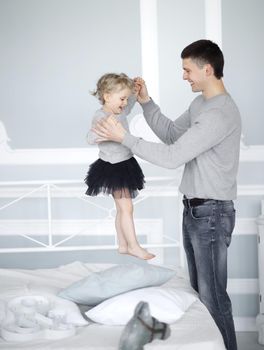 dad plays with daughter on the bed in the bedroom.photo with copy space