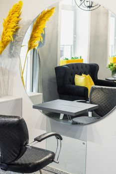 Interior of modern beauty and hairdresser salon with armchair and mirror in yellow and black tones.