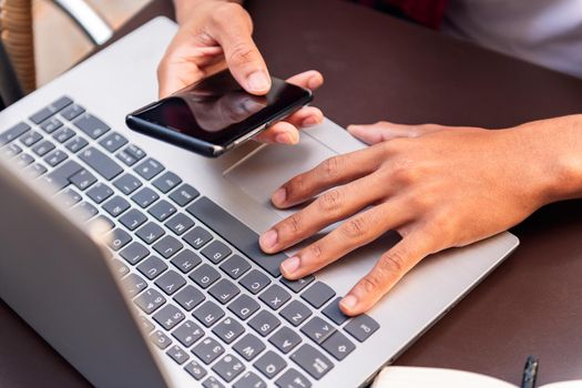 hands of an unrecognizable man working with his computer and phone, concept of technology and urban lifestyle