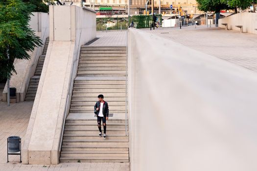 young latin man with backpack walking down city stairs, concept of urban lifestyle