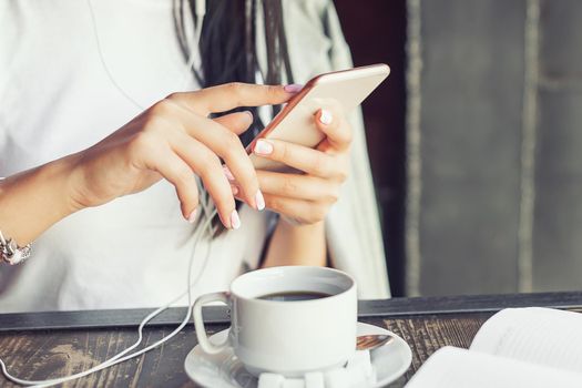Hands of young woman using her mobile phone in the cafe.