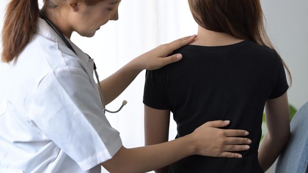 Female physiotherapists treating to female patients with back injuries back for muscle recovery.