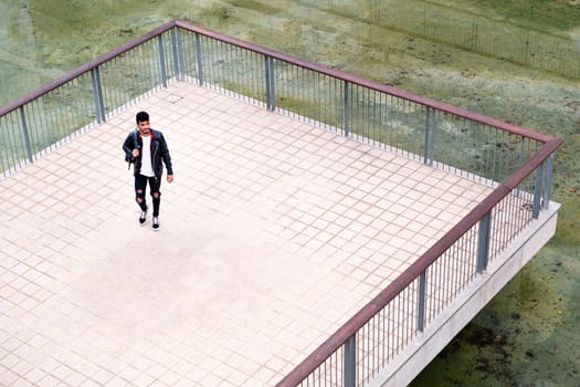 young urban man walking by the lake in a city park, concept of urban lifestyle
