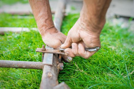 hand of an elderly man twisting the nut with a wrench outdoors. Repair by wrench.