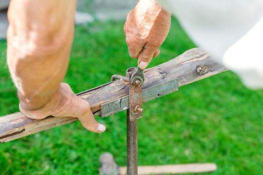 hand of an elderly man twisting the nut with a wrench outdoors. Repair by wrench.