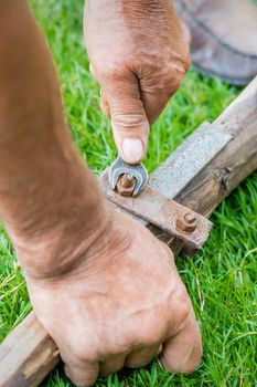 hand of an elderly man twisting the nut with a wrench outdoors. Repair by wrench.