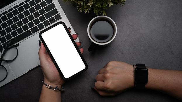 Trendy businesswoman wearing smear watch and using mobile phone at her workplace.