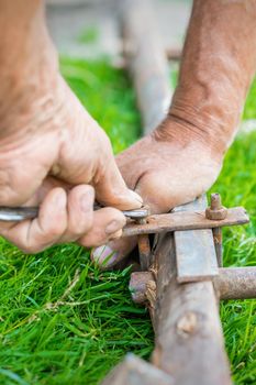hand of an elderly man twisting the nut with a wrench outdoors. Repair by wrench.