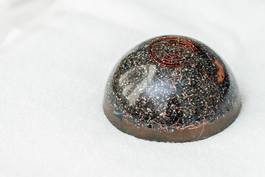 Close up of hot black massage stone sitting on white towel in spa.