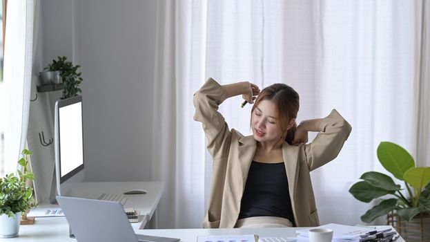 Smiling female employee relaxing at comfortable office chair.