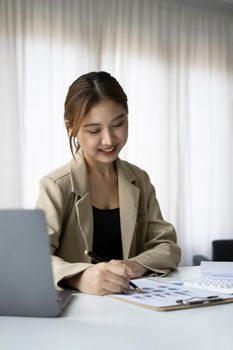 Positive female entrepreneur checking financial documents at her workplace.