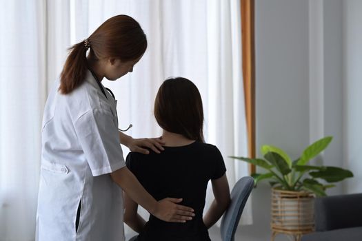 Physiotherapist examining female patient with back injuries in clinic. Physical therapy concept.