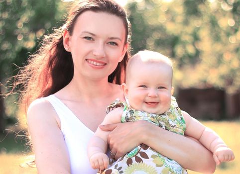 happy mother holds a little daughter in her arms.