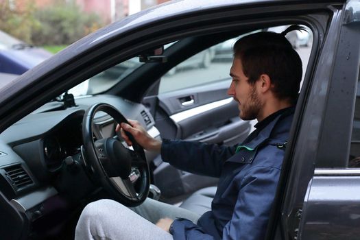 confident man sitting behind the wheel of a car.
