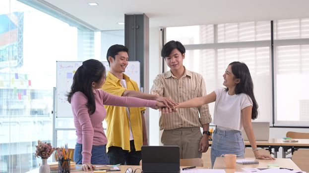 Young businesspeople joining fists each other, showing support and team spirit together, celebrating corporate achievement.