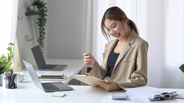 Charming female freelancer working online at er home office.