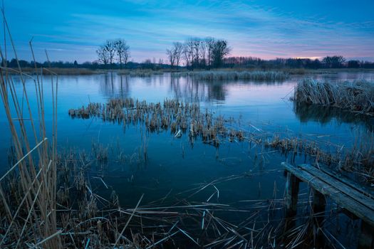 A frozen lake and an old wooden bridge, evening view