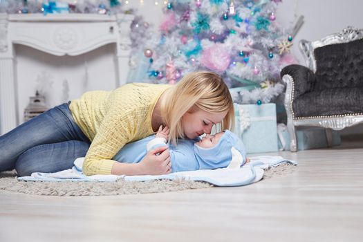 mom hugs her baby near the Christmas tree. the concept of Christmas