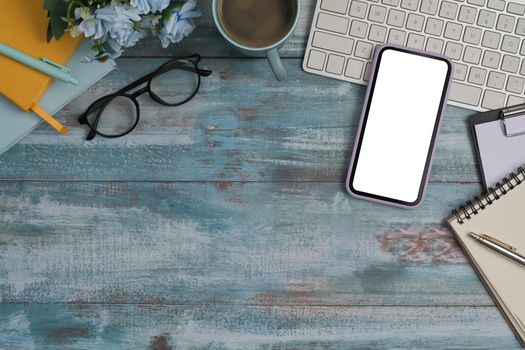 Top view smart phone, glasses, notebook and coffee cup on wooden background with copy space.