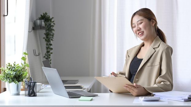 Cheerful young woman office worker working in bright office.