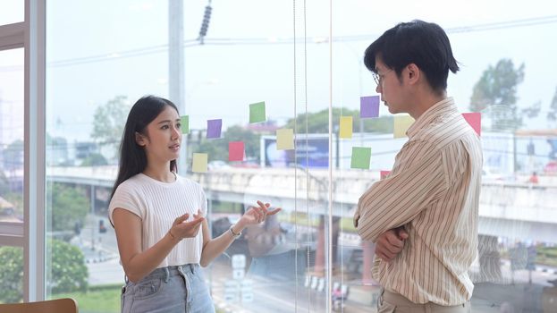 Focused young woman sharing ideas or startup business plan with her colleague.