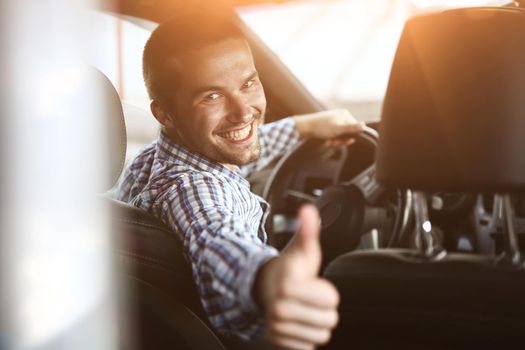 close up. modern man sitting in a car and showing his thumb up.