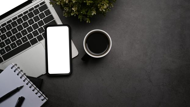 Mobile phone, laptop computer and coffee cup on dark stone background. Flat lay, Top view.