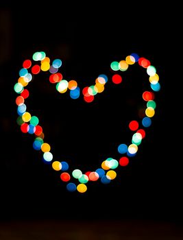 Bokeh with the shape of a heart with multi colors. Festive lights bokeh background, 