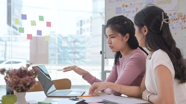 Young creative woman sharing new business ideas with her colleagues during meeting in office.